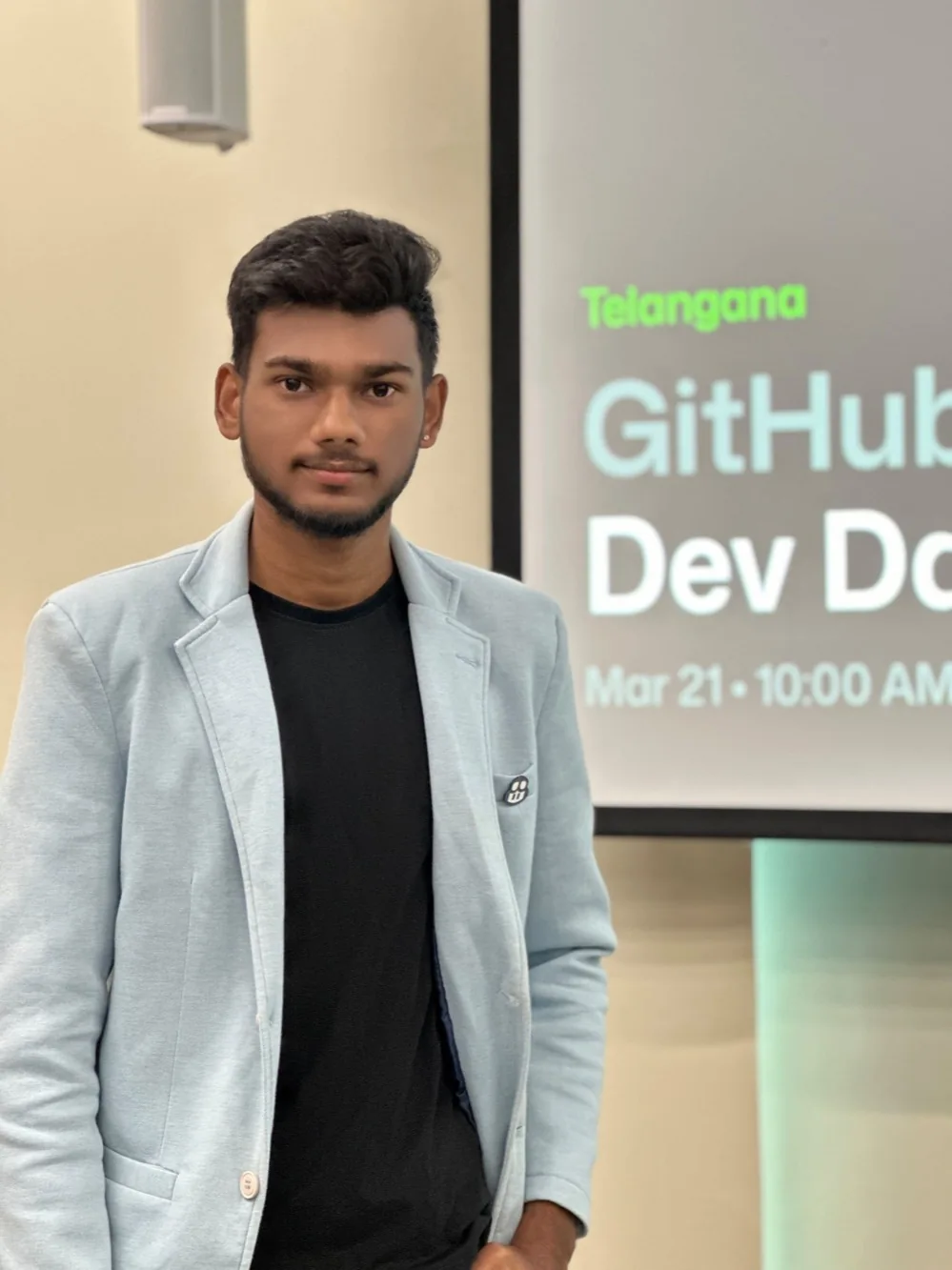 Ram Surya Chelluboyina in a light blazer beside a developer-event screen.